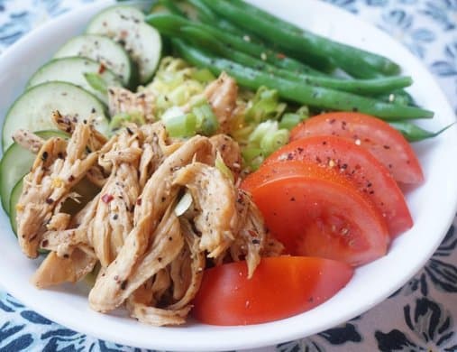 A bright bowl of shredded chicken, sliced cucumbers, tomatoes, and green beans.