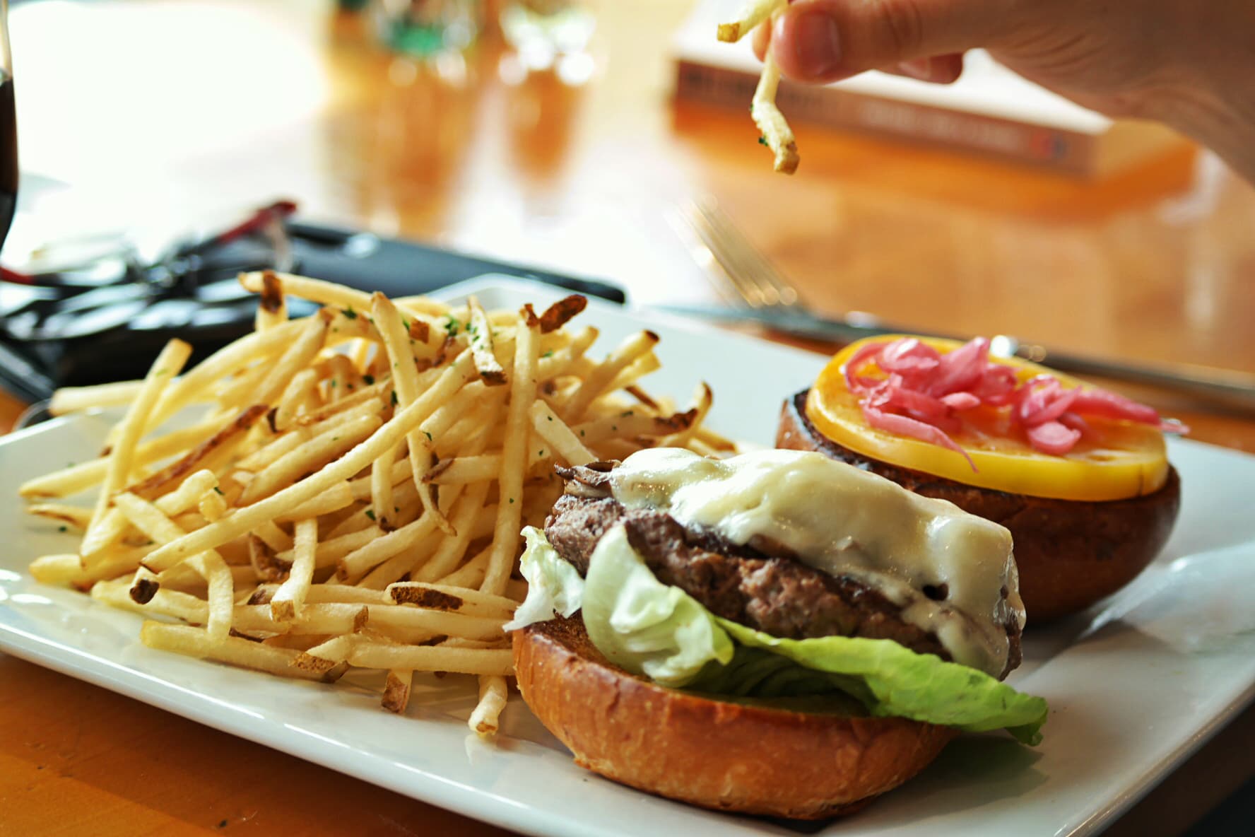 A burger with cheese and lettuce, a side of crispy fries, on a white plate — food without shame.